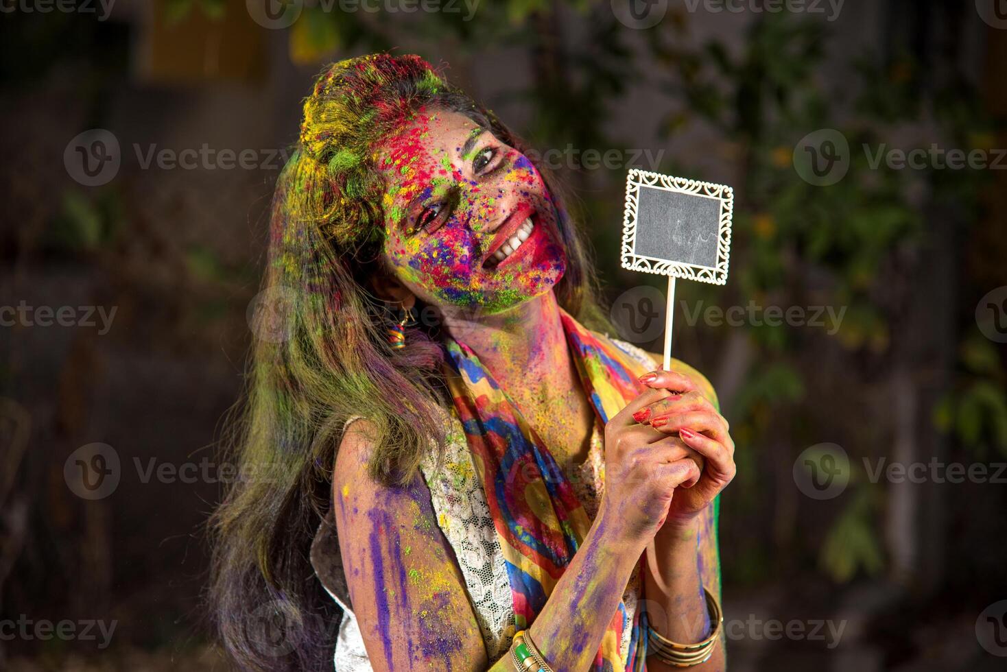 Young girl holding the small board on the occasion of Holi festival with faces painted with powdered colors, with a colour splash. photo