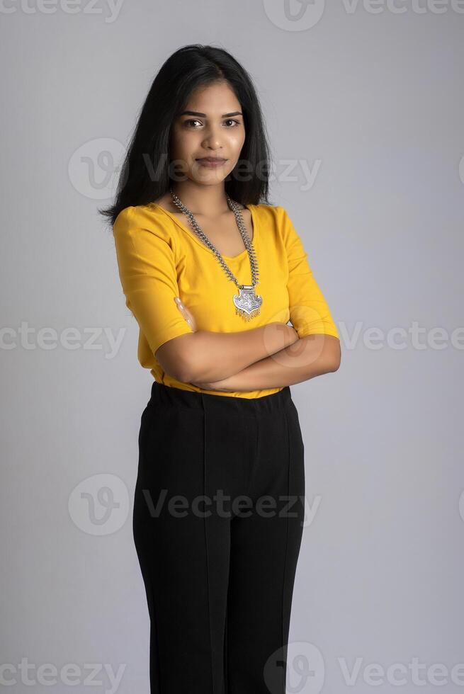 Portrait of a beautiful, smiling, emotional young woman posing with hands-folded on gray background. photo