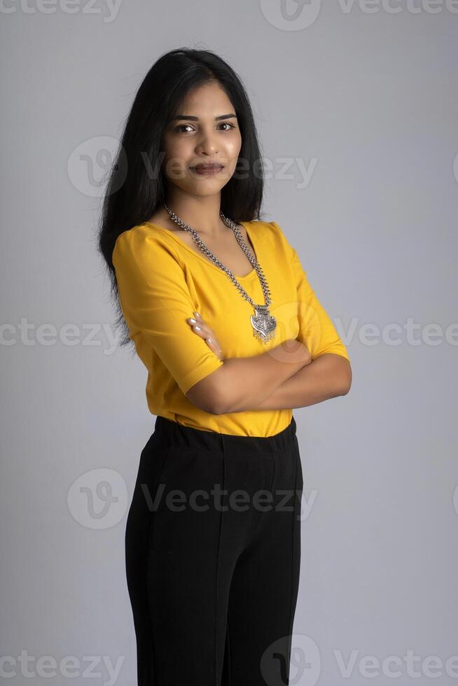 Portrait of a beautiful, smiling, emotional young woman posing with hands-folded on gray background. photo