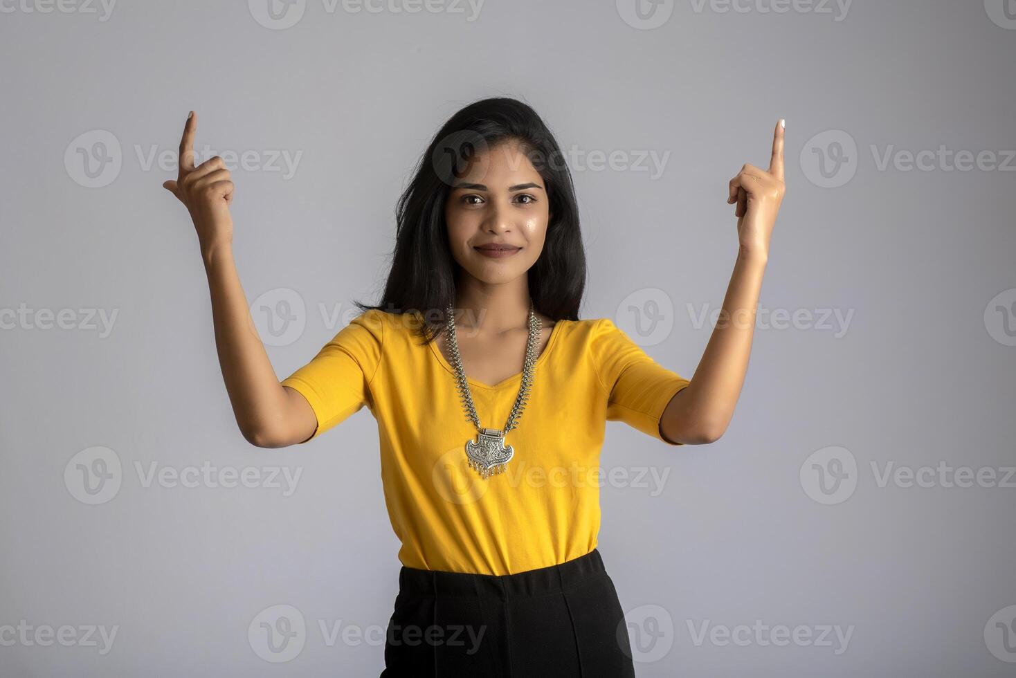 Portrait of a successful cheerful young girl holding and presenting something on hand with a happy smiling face. photo