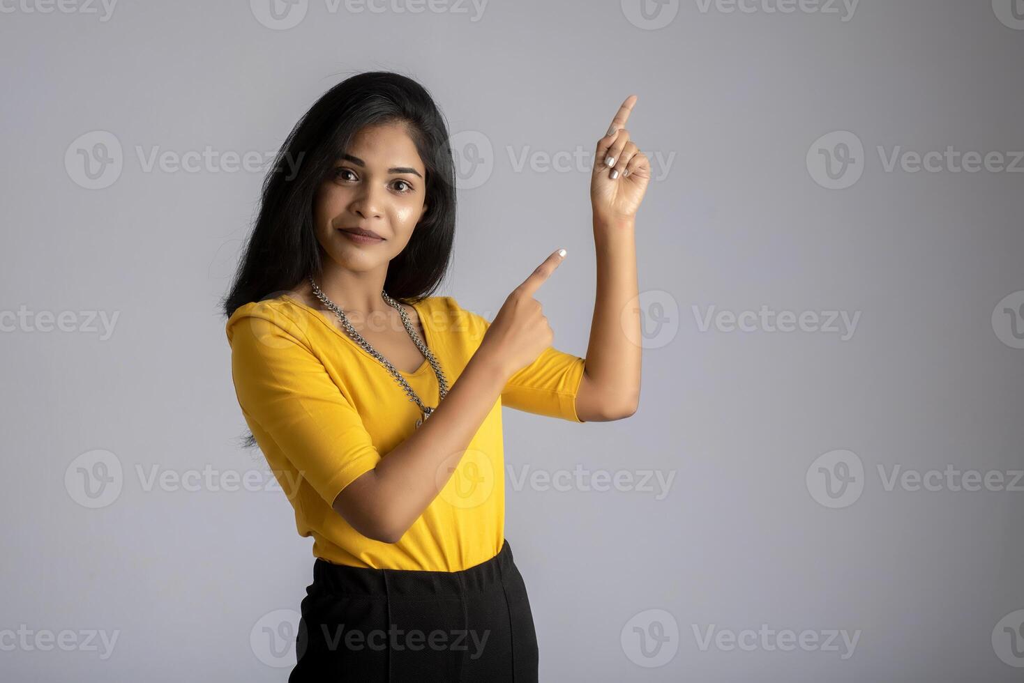 Portrait of a successful cheerful young girl holding and presenting something on hand with a happy smiling face. photo