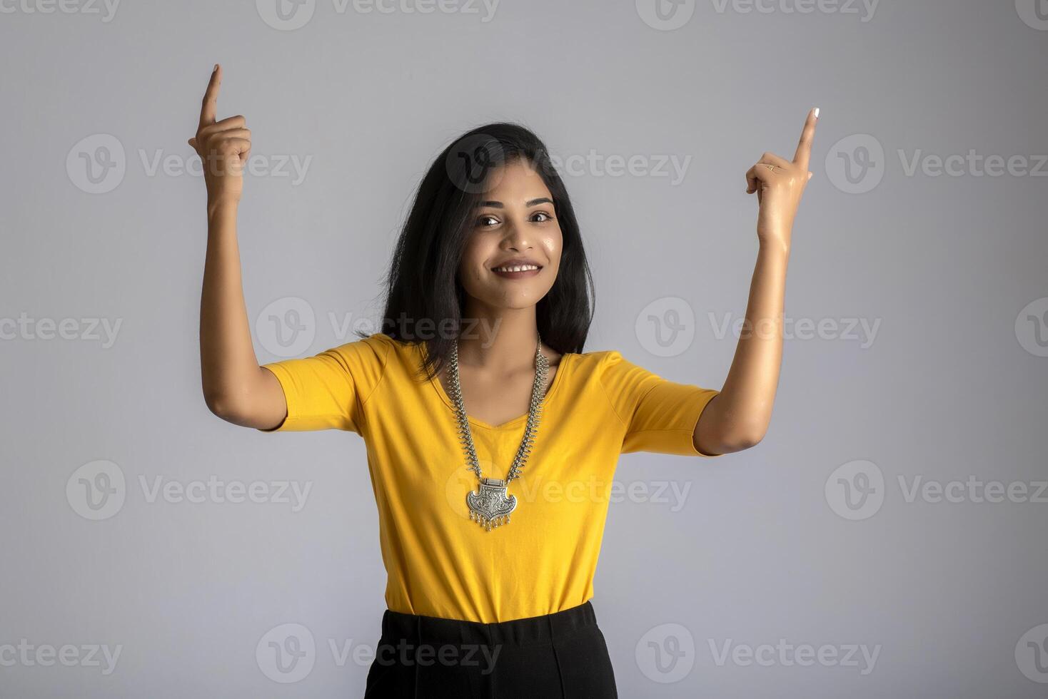 Portrait of a successful cheerful young girl holding and presenting something on hand with a happy smiling face. photo