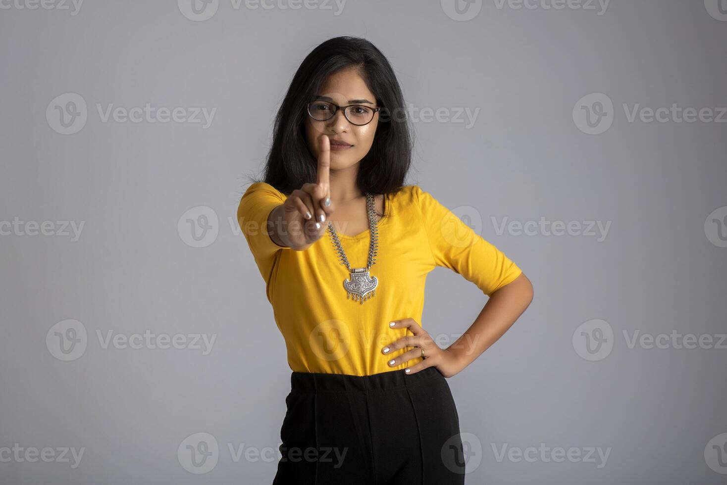 Portrait of a beautiful girl showing stop sign with palms on a grey background photo