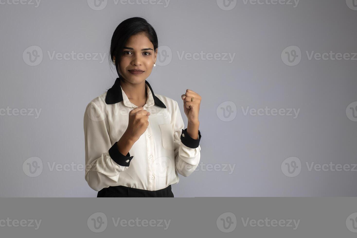 Young smiling girl showing happiness of success on a grey background photo