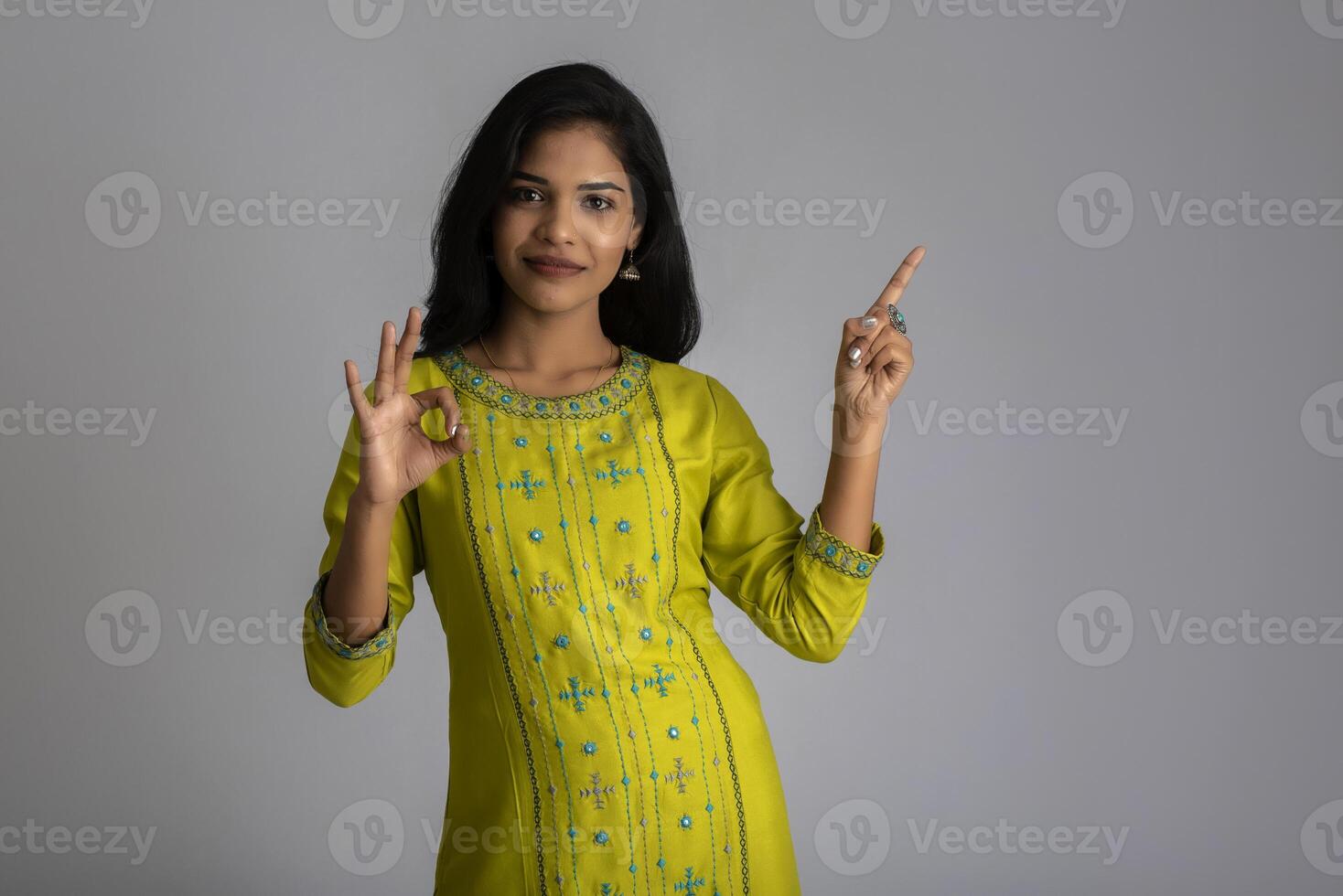 Portrait of a successful cheerful young girl holding and presenting something on hand with a happy smiling face. photo