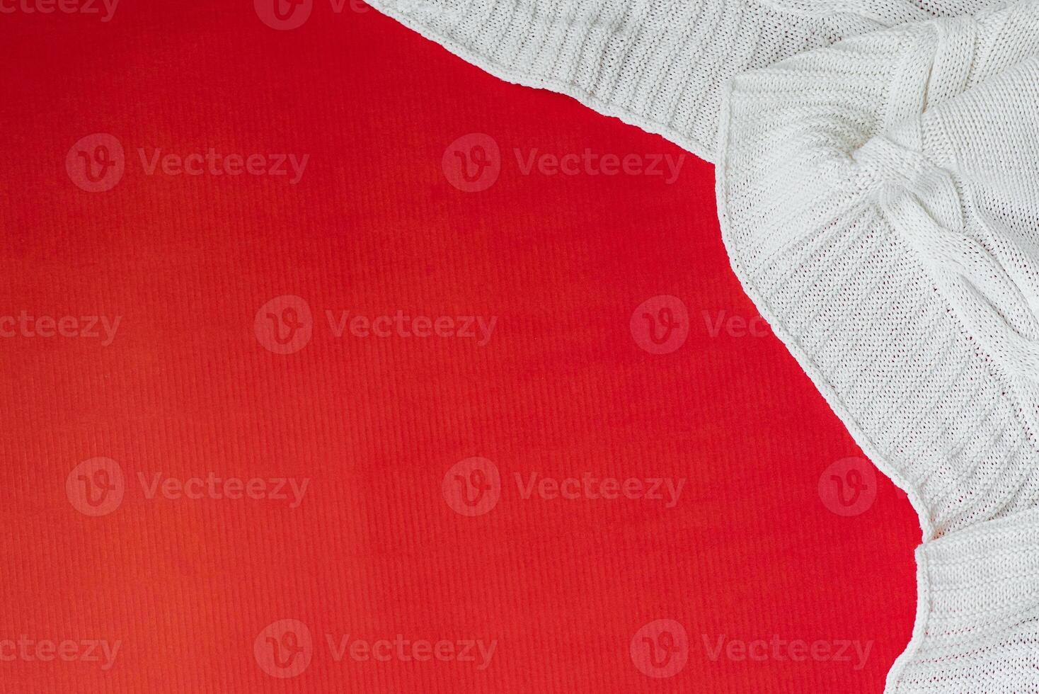 White knitted plaid on a red background in the corner. Flat lay. Copy Space photo