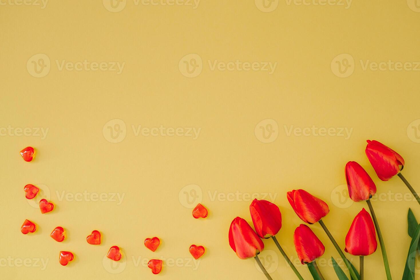 Bouquet of tulips and red hearts on a yellow background with copying space Festive greeting card for Valentine's Day photo