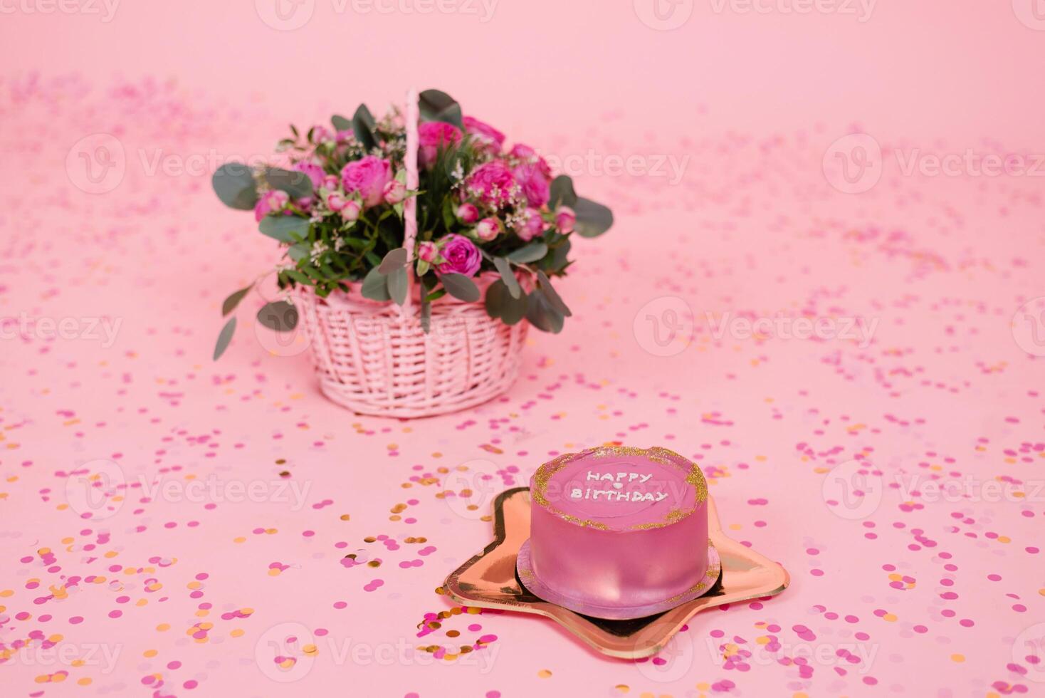 Stylish pink and gold festive Korean bento cake on a golden plate in the shape of a star on a pink background with confetti and a basket with fuchsia roses photo