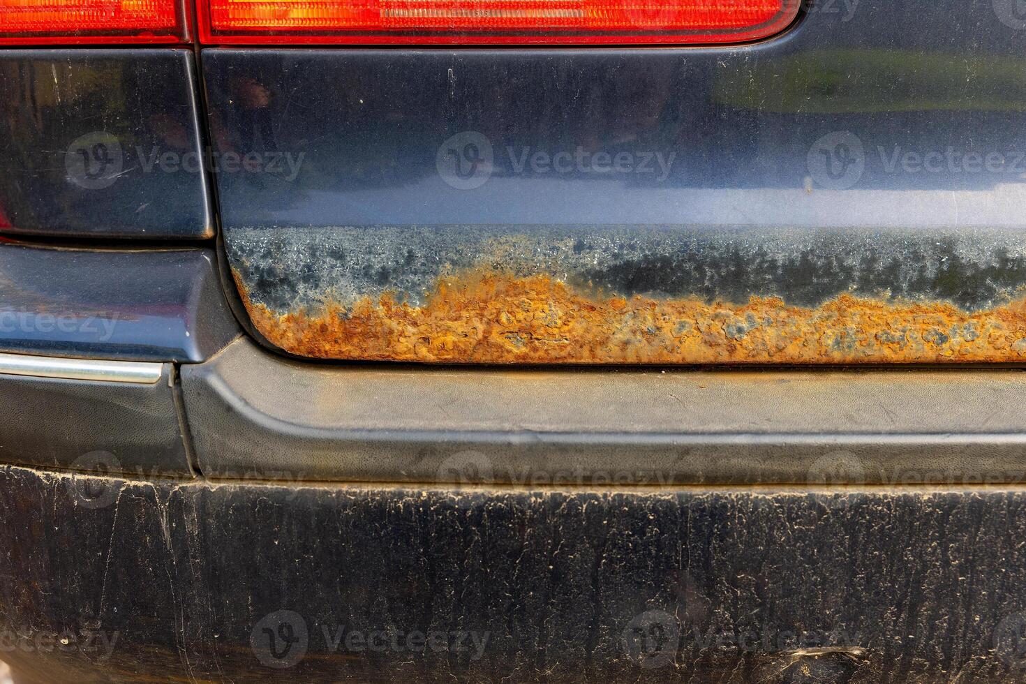 A close-up view of a car's rear bumper showing significant rust damage photo