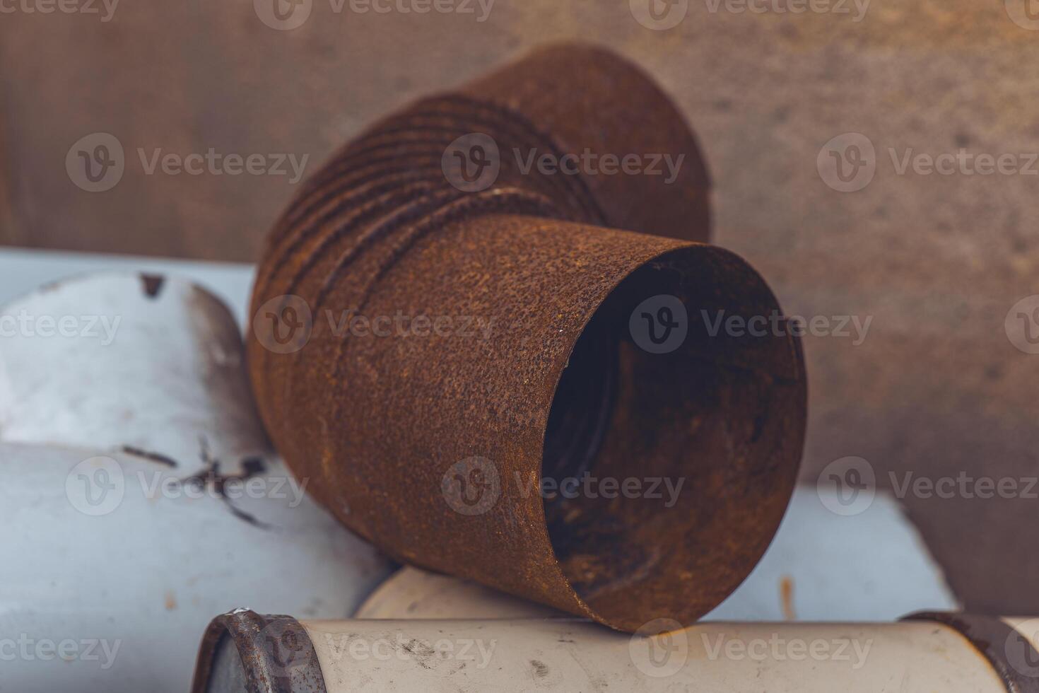 A rusted metal pipe sits on top of a white surface photo