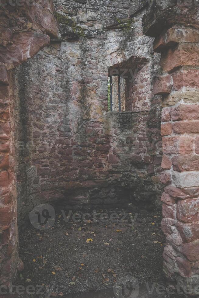 A small, windowless room in a stone ruin with a barred window overlooking the courtyard photo
