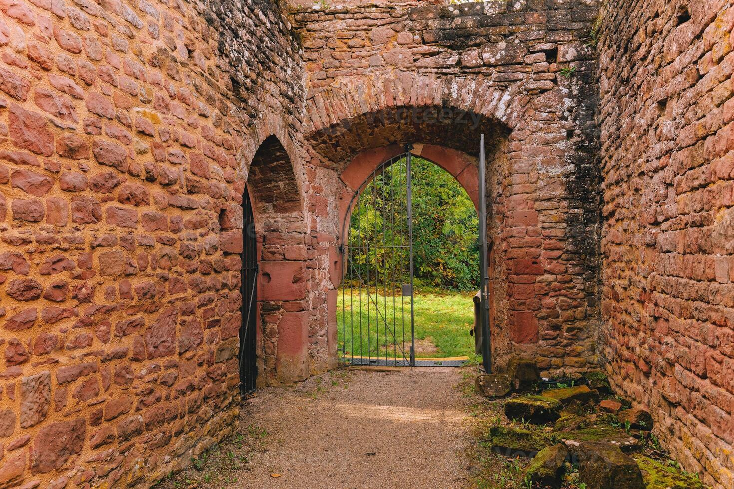 stone archway with a gate in front of it. The gate is open and the archway is dark photo