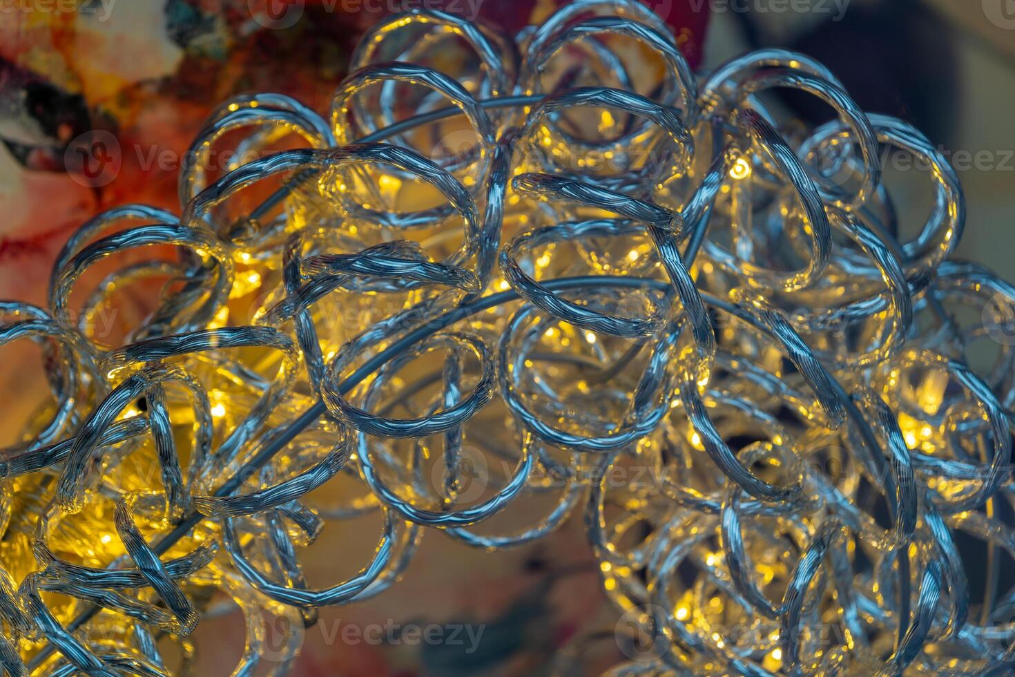 A close-up of silver fairy lights twisted into a decorative shape, with warm yellow bulbs illuminating the wires photo