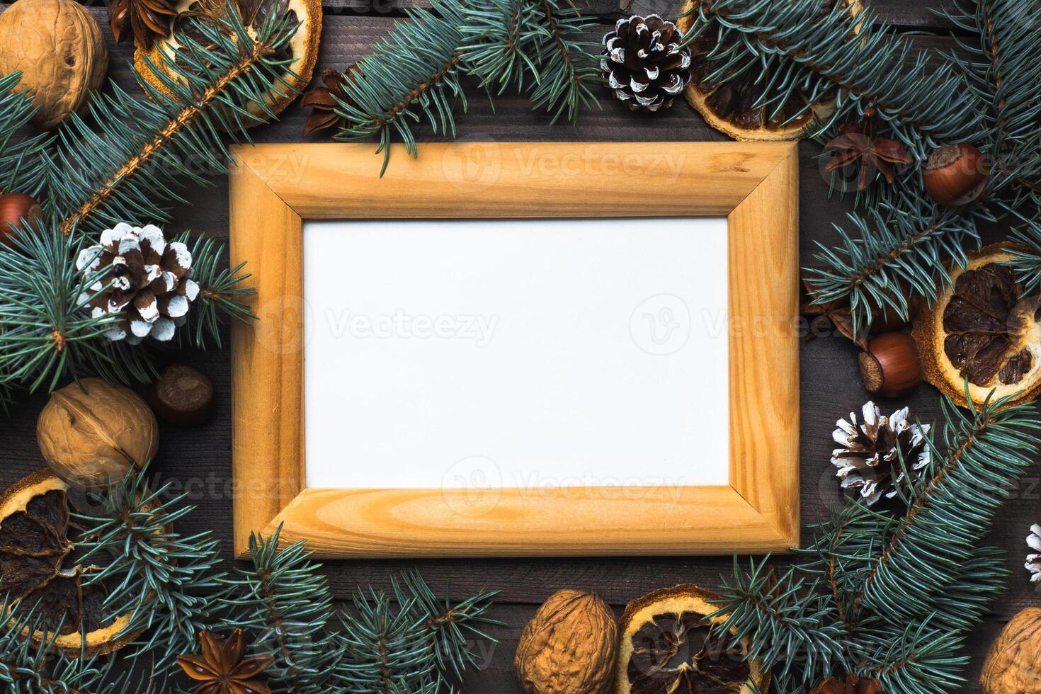 Frame of Christmas tree cones oranges nuts on dark wooden background. Copy space. Flat lay. Wooden frame and space for text. photo