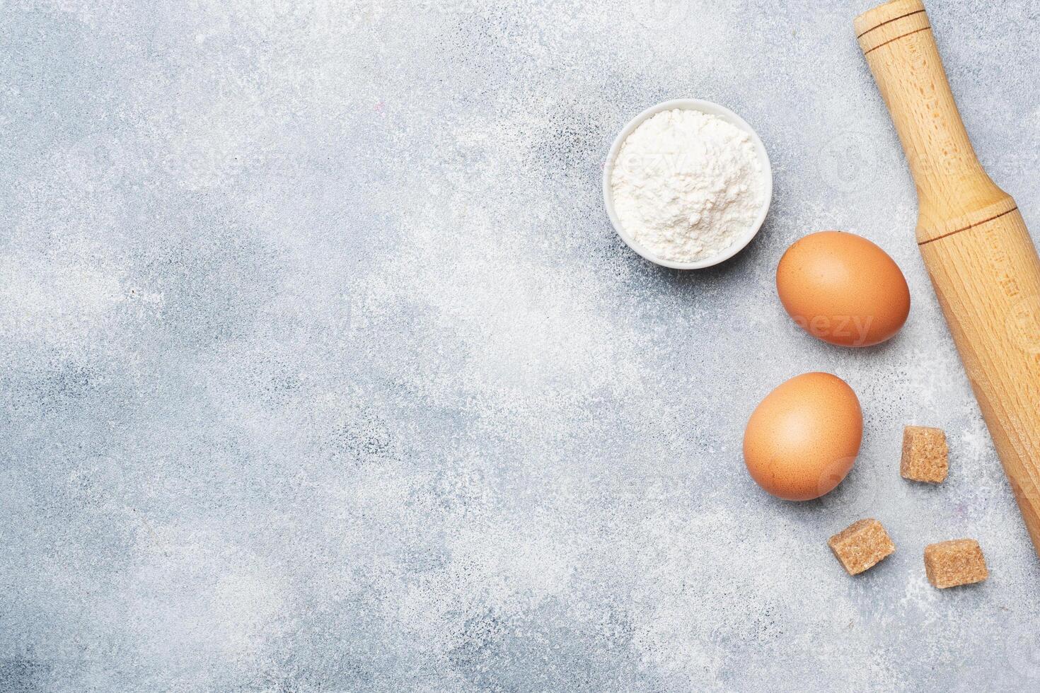 Ingredients for baking cookies, cupcakes and cake. Raw foods eggs flour sugar on a grey background with copy space. photo
