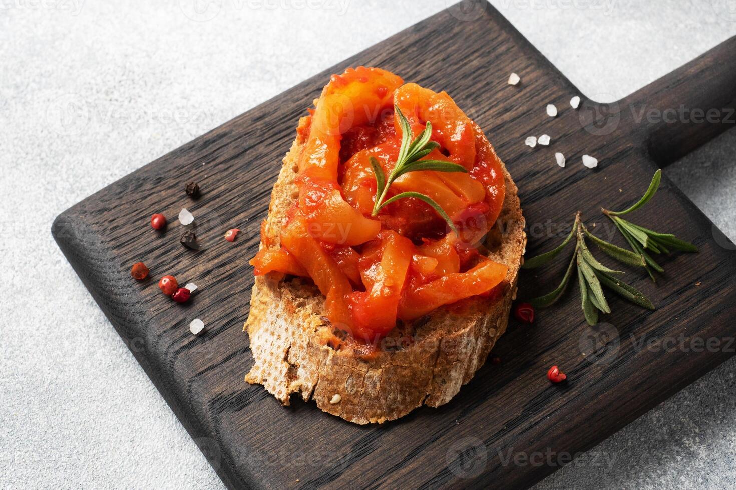 Whole grain bread sandwiches with canned peppers with tomato on a wooden cutting Board. Gray concrete background with Copy space. photo