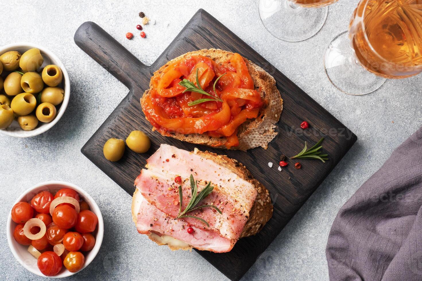 Whole grain bread sandwiches with cream cheese, bacon and canned peppers with tomato on a wooden cutting Board. Gray concrete background with Copy space. photo