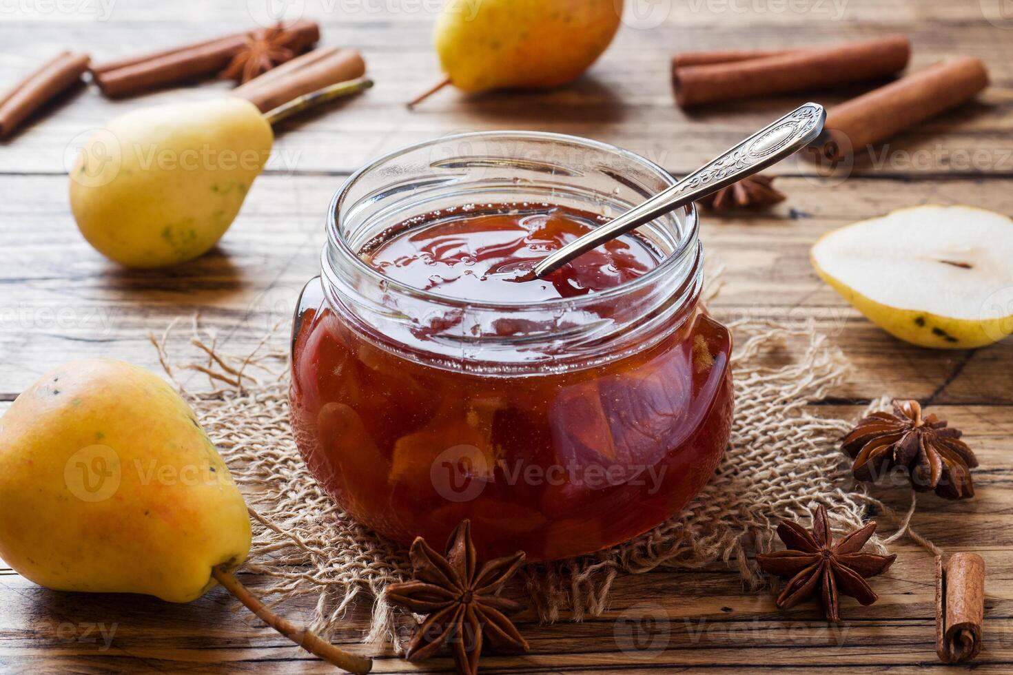 Homemade pear jam in a jar and fresh pears on a wooden background. photo
