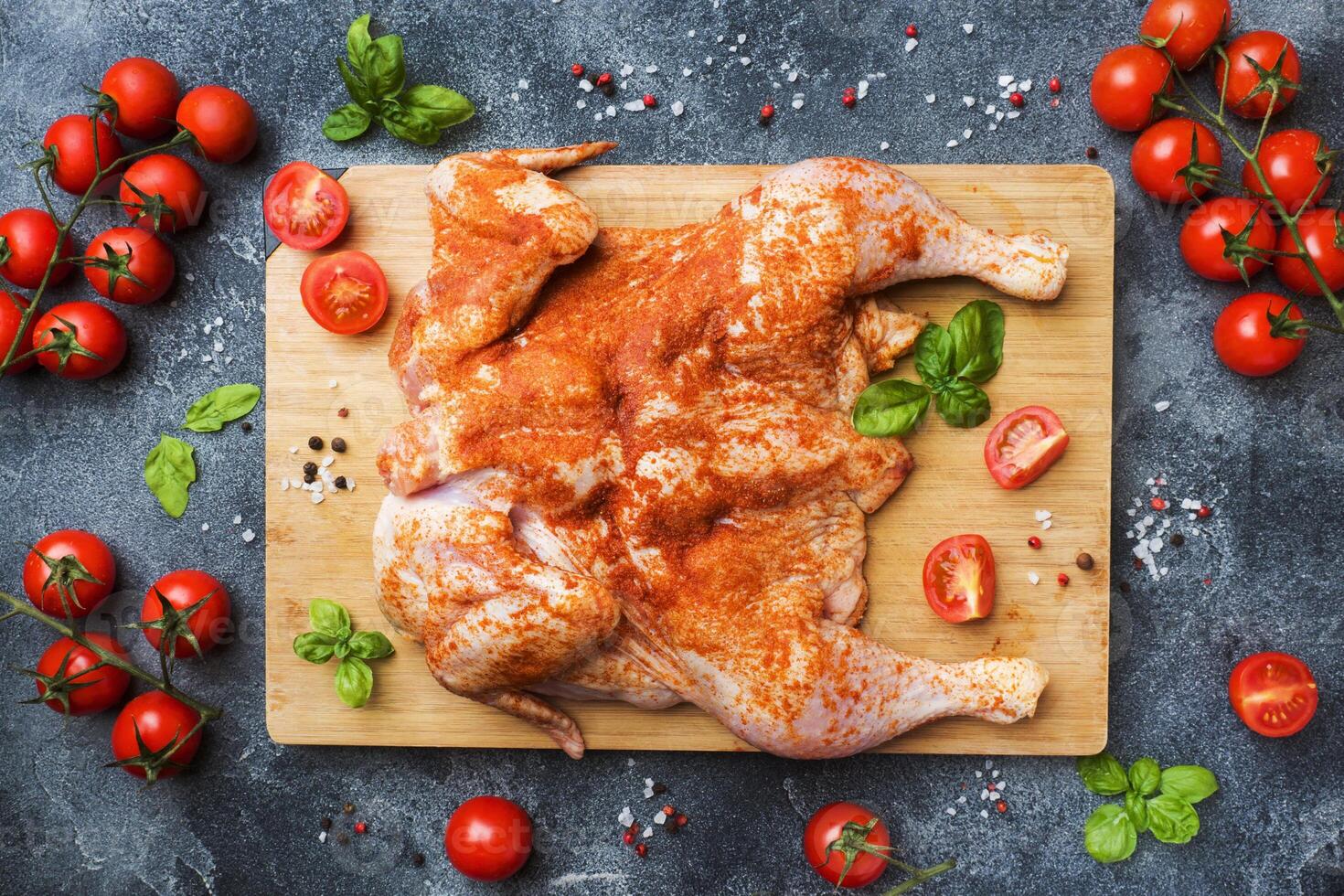 Raw chicken tobacco on a wooden Board with spices and vegetables. photo