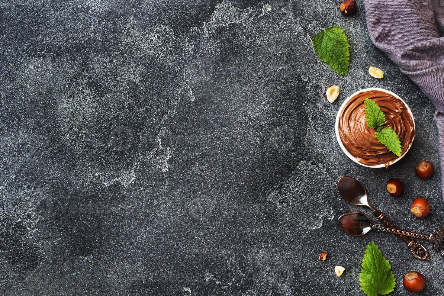 Nougat nut chocolate in a plate on a dark concrete background with hazelnut nuts. Concept of Breakfast. Copy space. photo