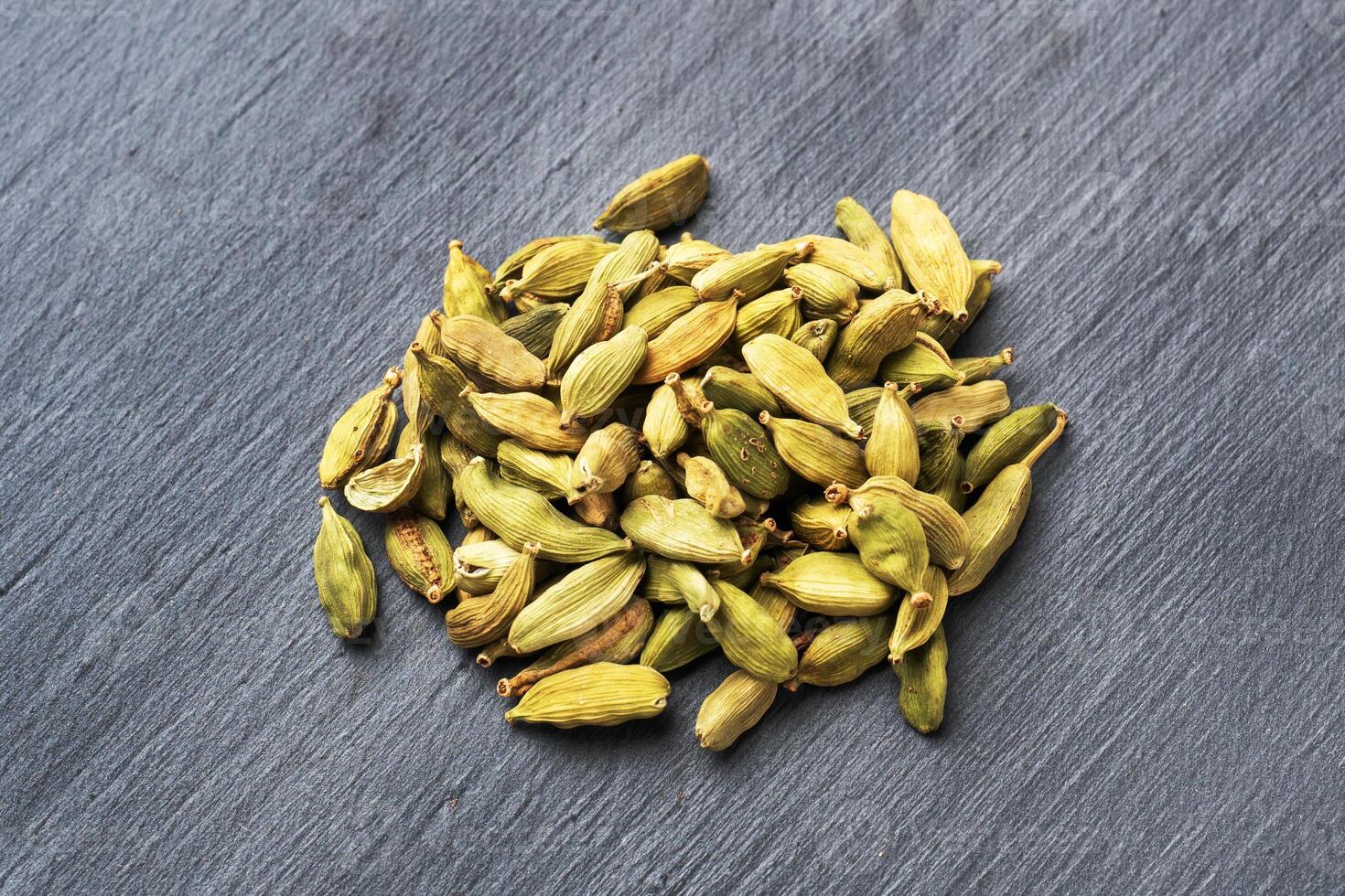 Fruits of dry whole cardamom on a black concrete background. Spicy Indian spice. photo