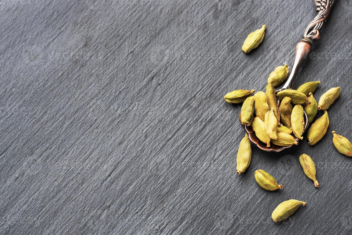 Fruits of dry whole cardamom on a black concrete background. Spicy Indian spice. photo