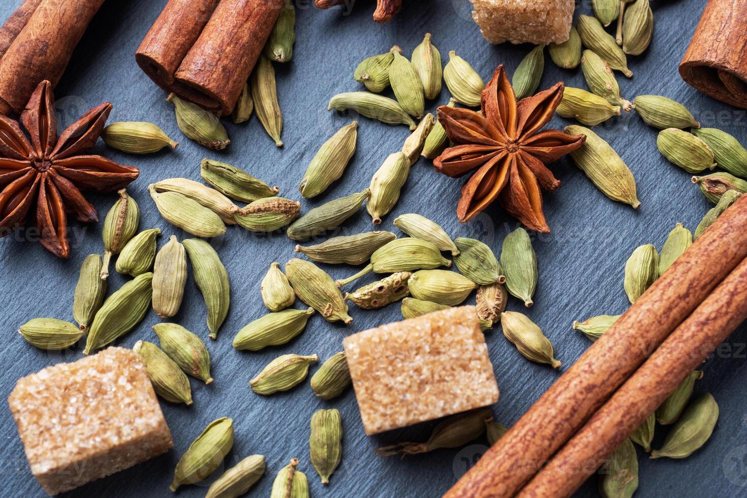 Whole grains of cardamom, a stick of cinnamon star anise and cane sugar. Close up. Ingredients for making the Indian drink masala tea. photo