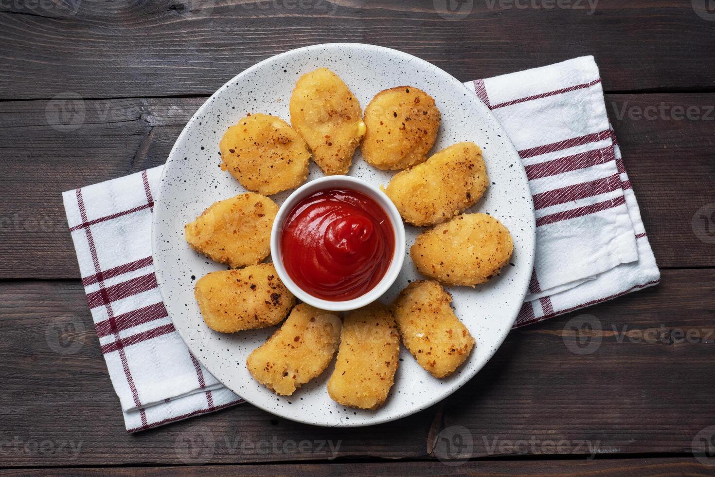 Fried chicken nuggets with tomato ketchup sauce. Wooden background. Copy space. photo