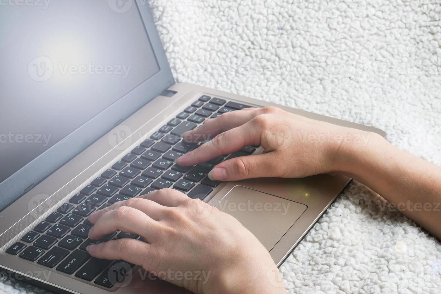 Woman sitting on a sofa working at computer hands. Close up. photo