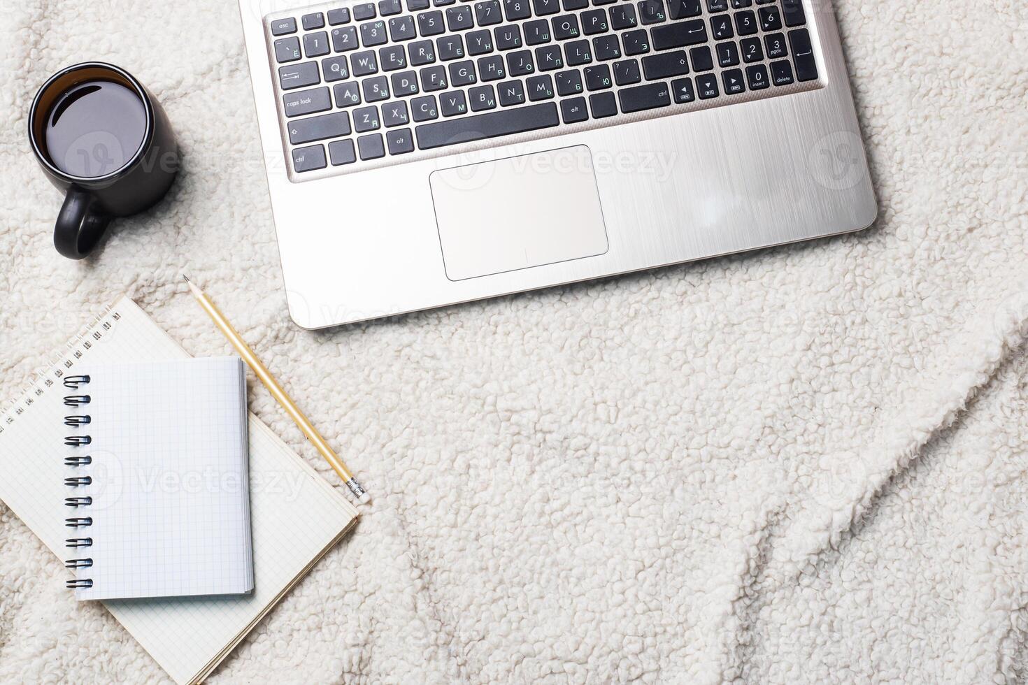 Notebook Computer and coffee lying on a white wool blanket. Concept of working and learning at home. Copy space. photo
