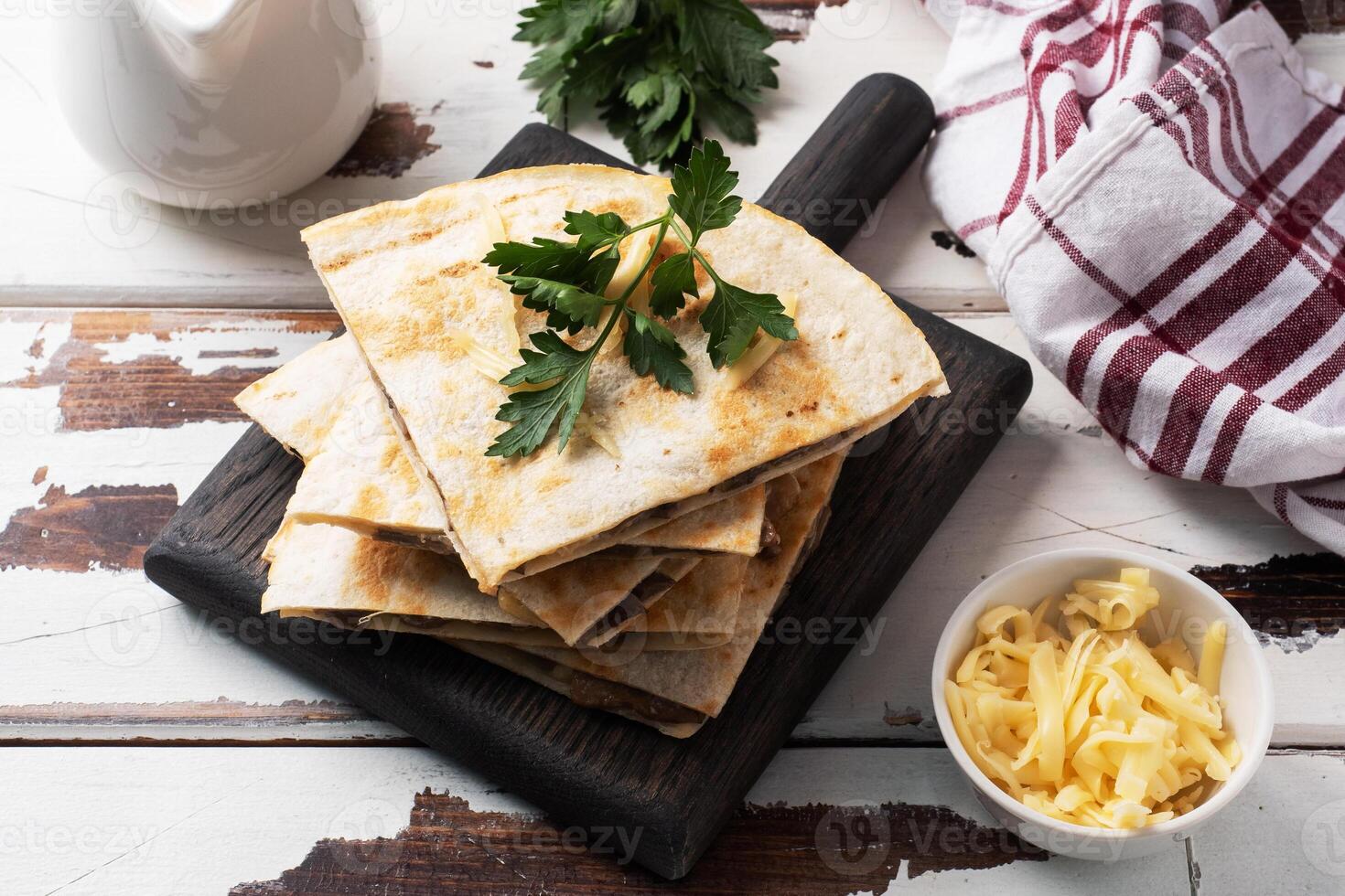 Pieces of quesadilla with mushrooms sour cream and cheese on a wooden stand with parsley leaves. Wooden background copy space. photo