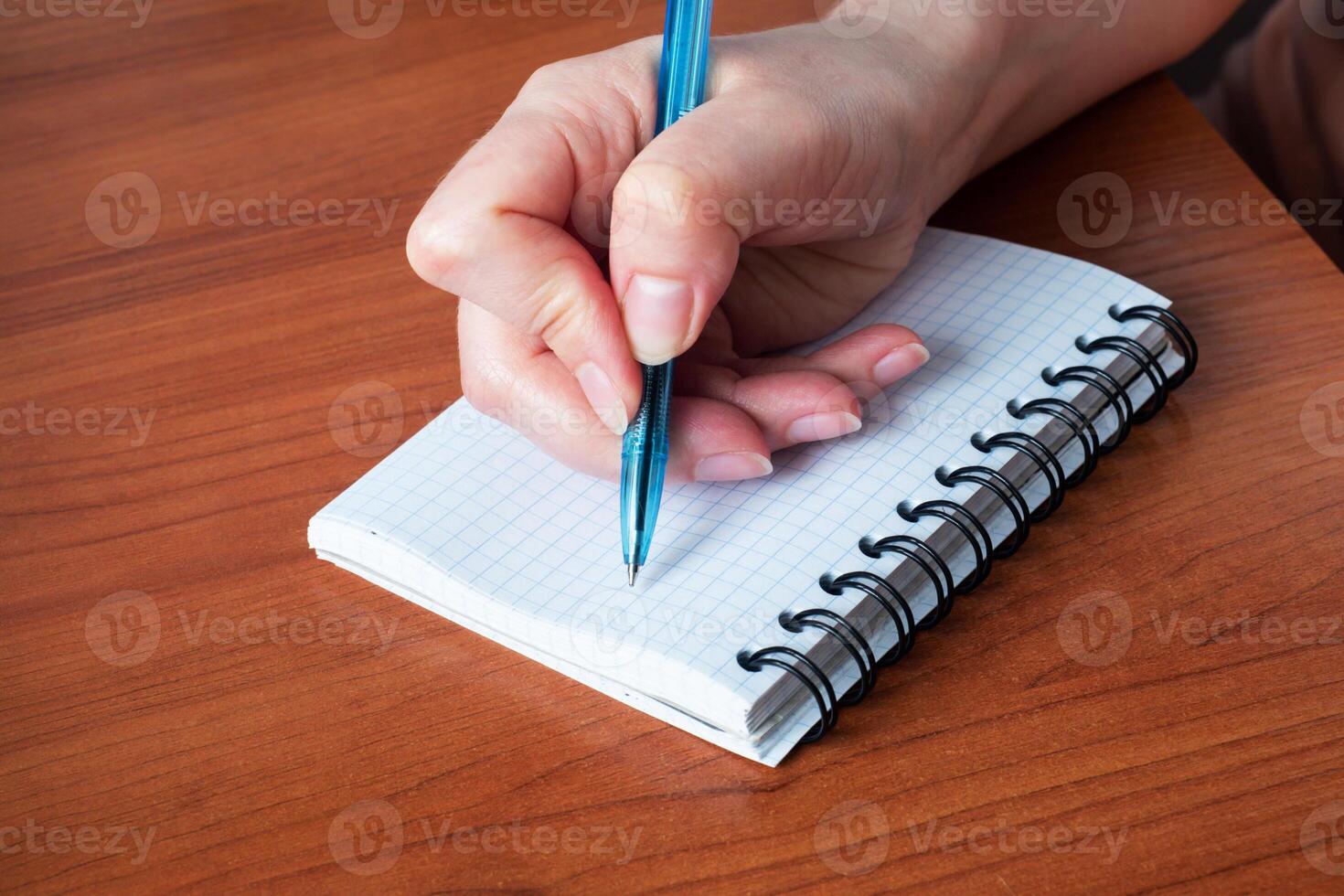 Hand write on notebook. Close up. Wooden table. photo