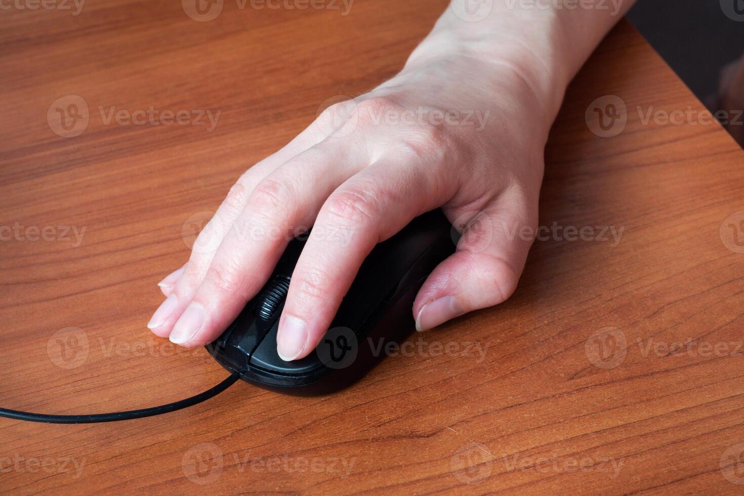 Hand holding computer mouse. Close up. Wooden table. photo