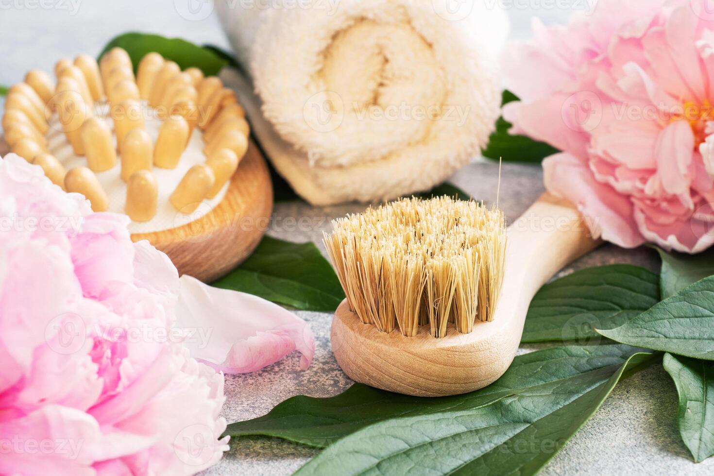 Concept SPA and Wellness. Massage brush, cosmetic oils and soap. Light background with peony flowers. photo