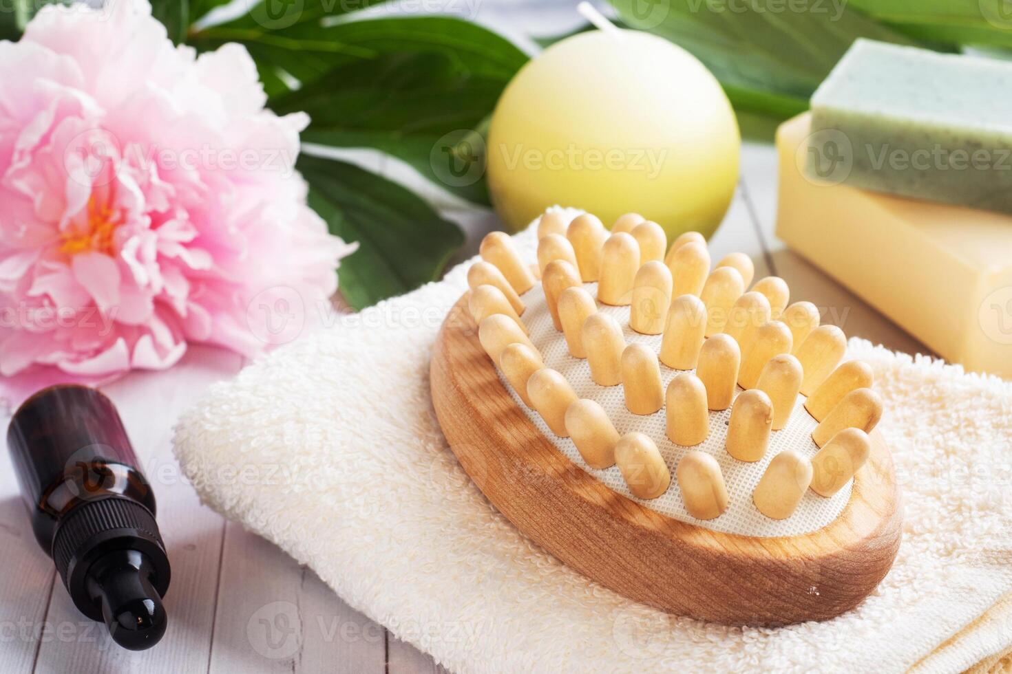 Concept SPA and Wellness. Massage brush, cosmetic oils and soap. Light background with peony flowers. photo