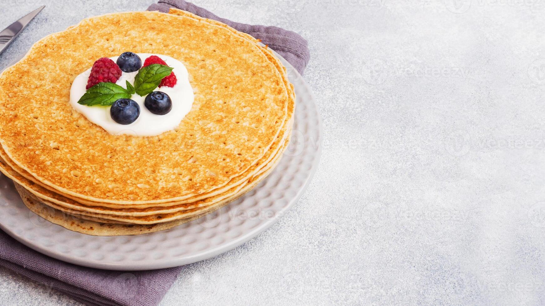 A stack of thin pancakes on a plate. Copy space. photo