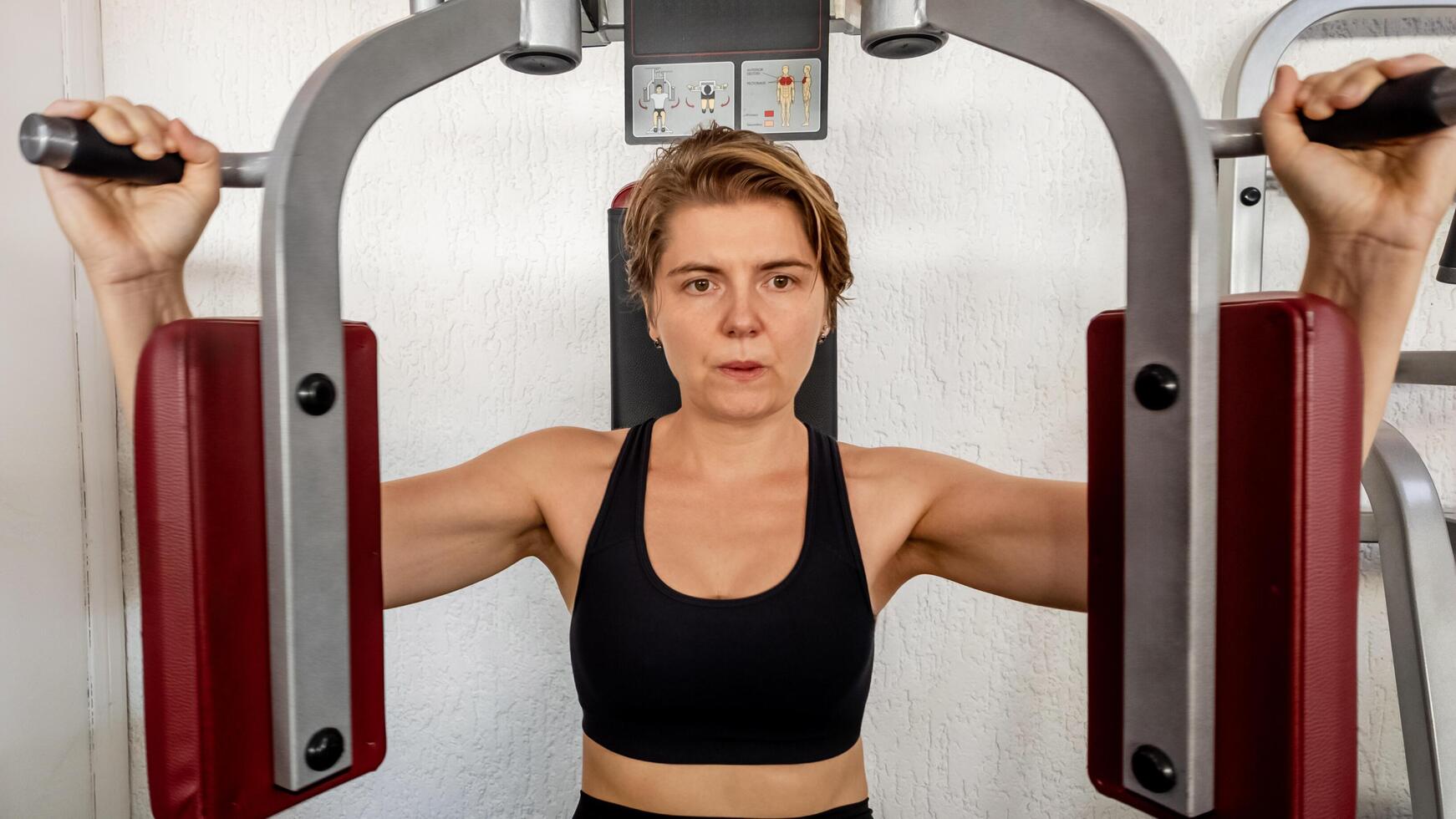 Caucasian woman exercising on a chest press machine in a gym, promoting physical fitness and healthy lifestyle concepts photo