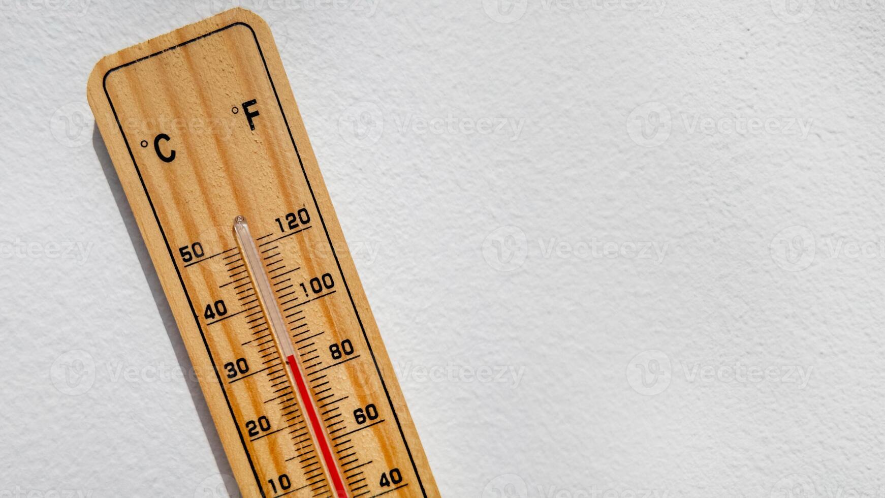 Wooden thermometer displaying high temperature in Celsius and Fahrenheit, representing heatwave and climate change issues photo