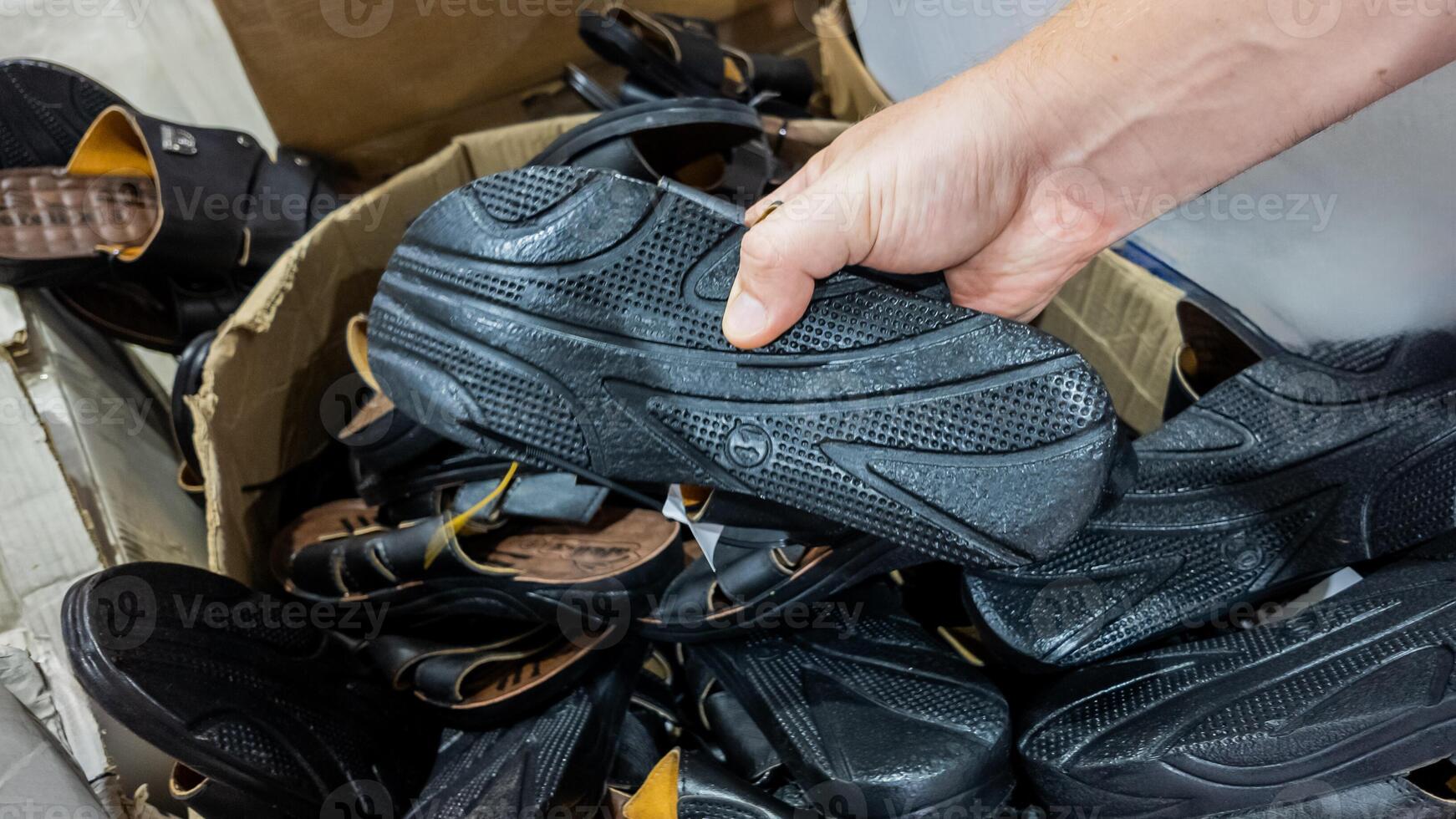 Hand selecting sandals from a pile highlighting quality control and manufacturing processes photo