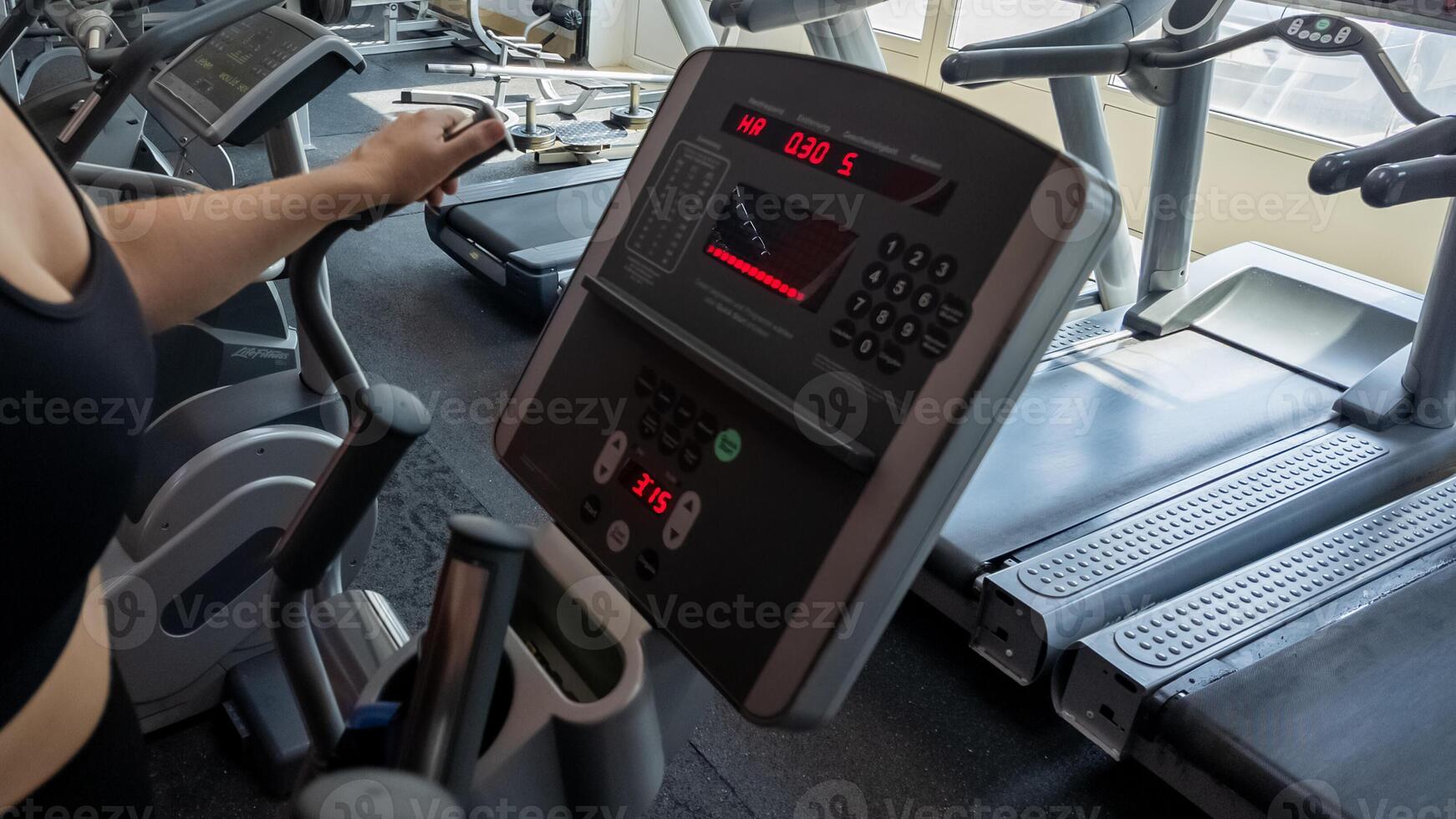 Woman using elliptical machine in a modern gym for fitness and cardio workout session photo