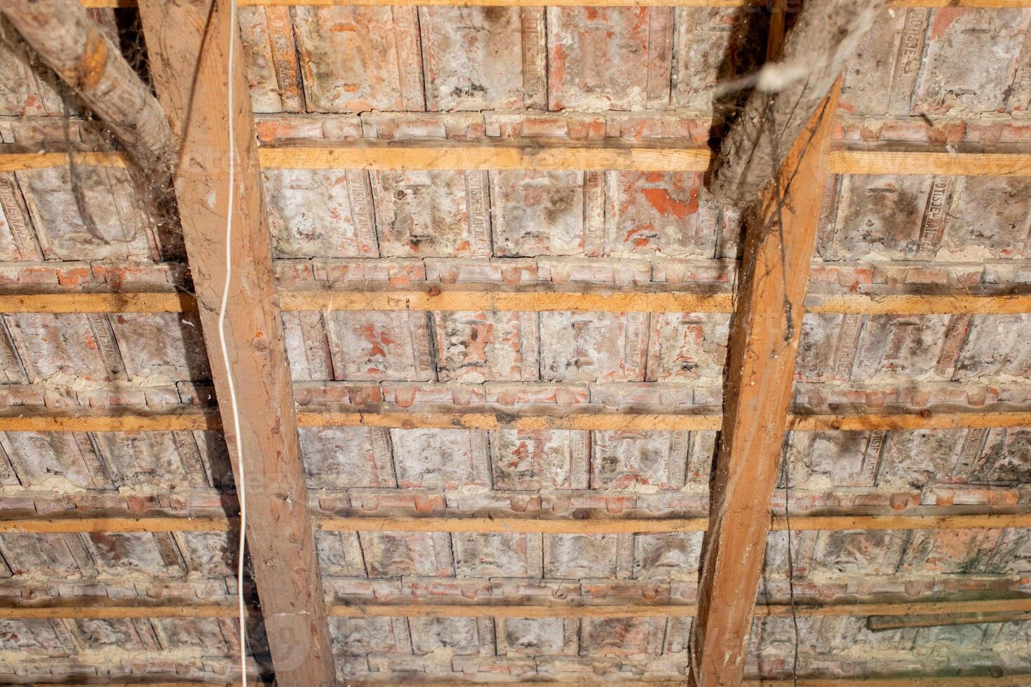Close up of a deteriorating wooden attic ceiling with exposed beams, related to home renovation and structural integrity issues photo