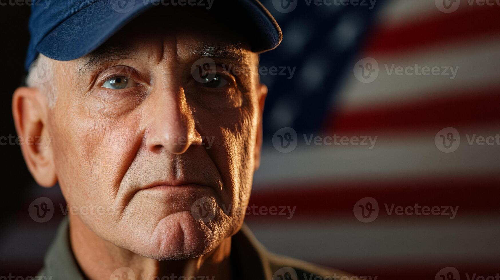 Elderly US veteran at sunrise with a shadowy American flag waving behind wearing a navy blue cap strong gaze warm golden light reflecting off face background with space for text photo