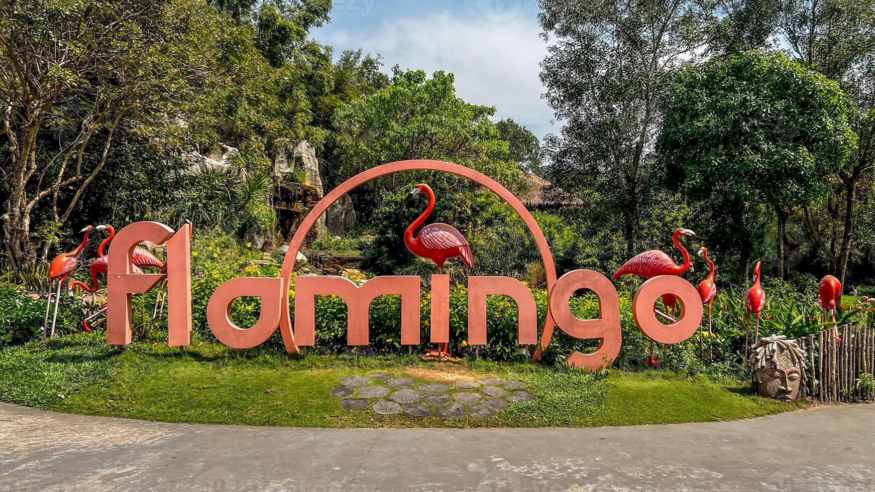 The vibrant entrance sign adorned with flamingo sculptures in a lush garden captures the essence of tropical tourism photo