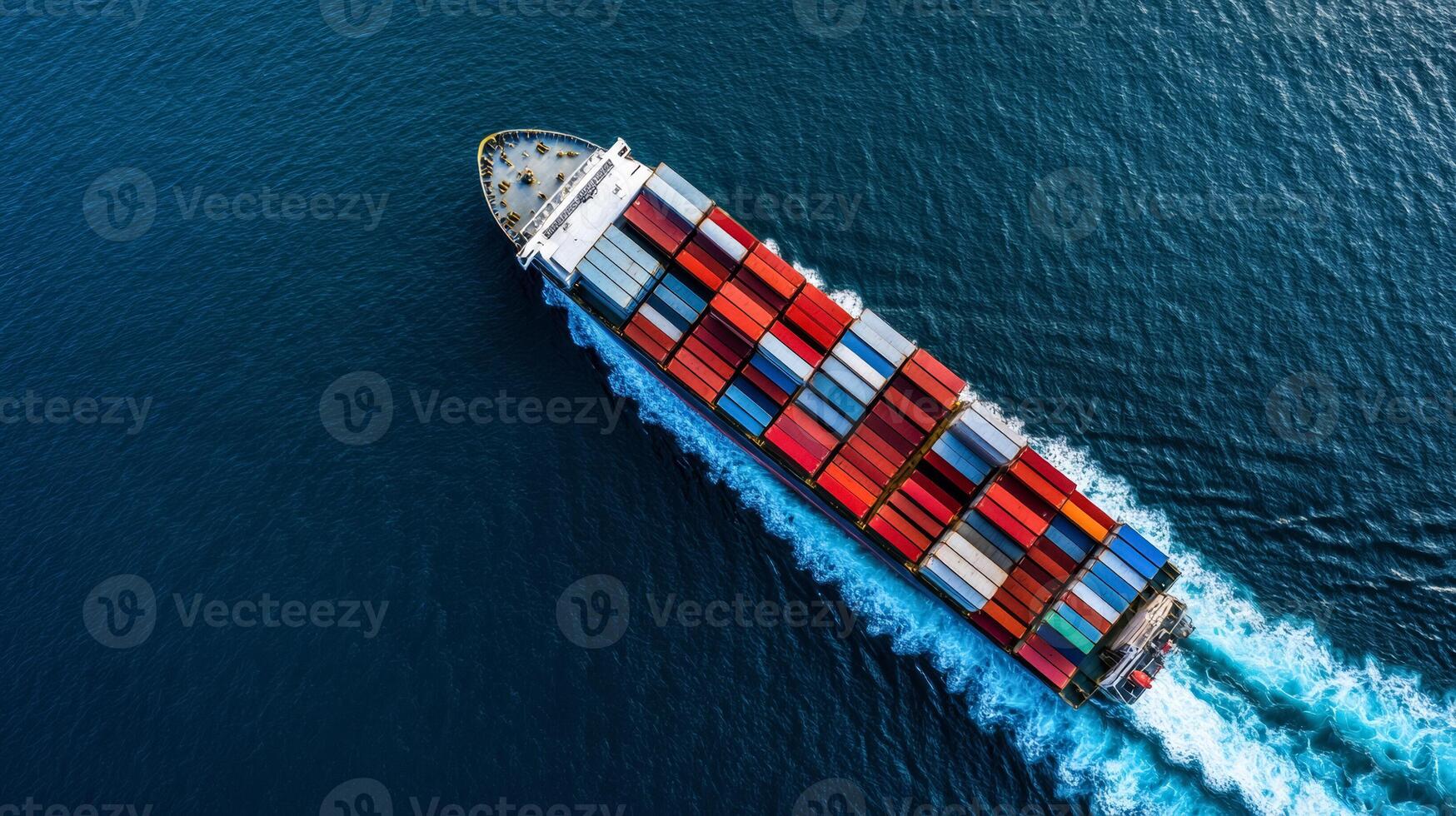 Birds eye shot of a cargo ship navigating through dark blue ocean waters containers stacked in organized patterns white wake trailing behind photo