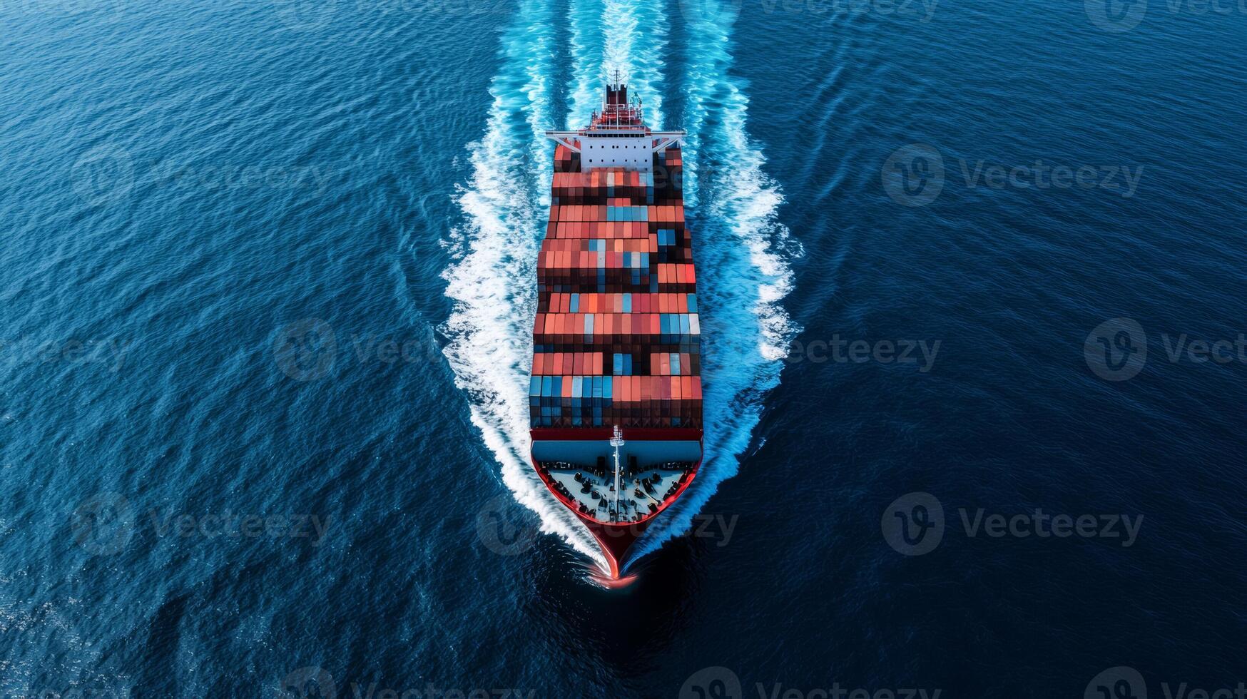 Birds eye shot of a cargo ship fully loaded with stacked containers cruising across the open ocean leaving a white foamy trail in its wake photo