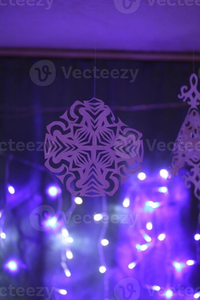 Traditional Christmas and New Year decorations. Garland lights and paper snowflakes, in a home interior. photo