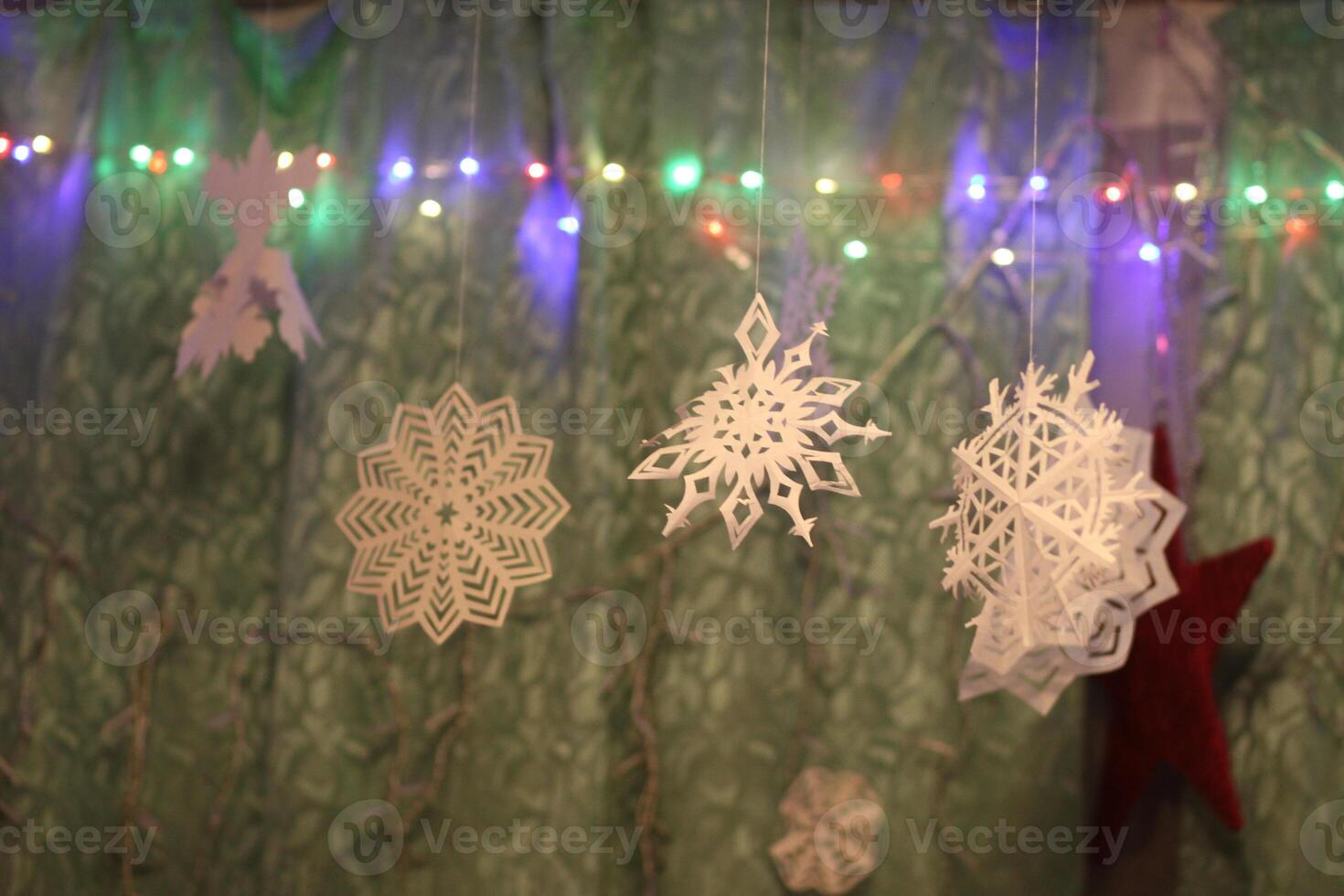 Traditional Christmas and New Year decorations. Garland lights and paper snowflakes, in a home interior. photo