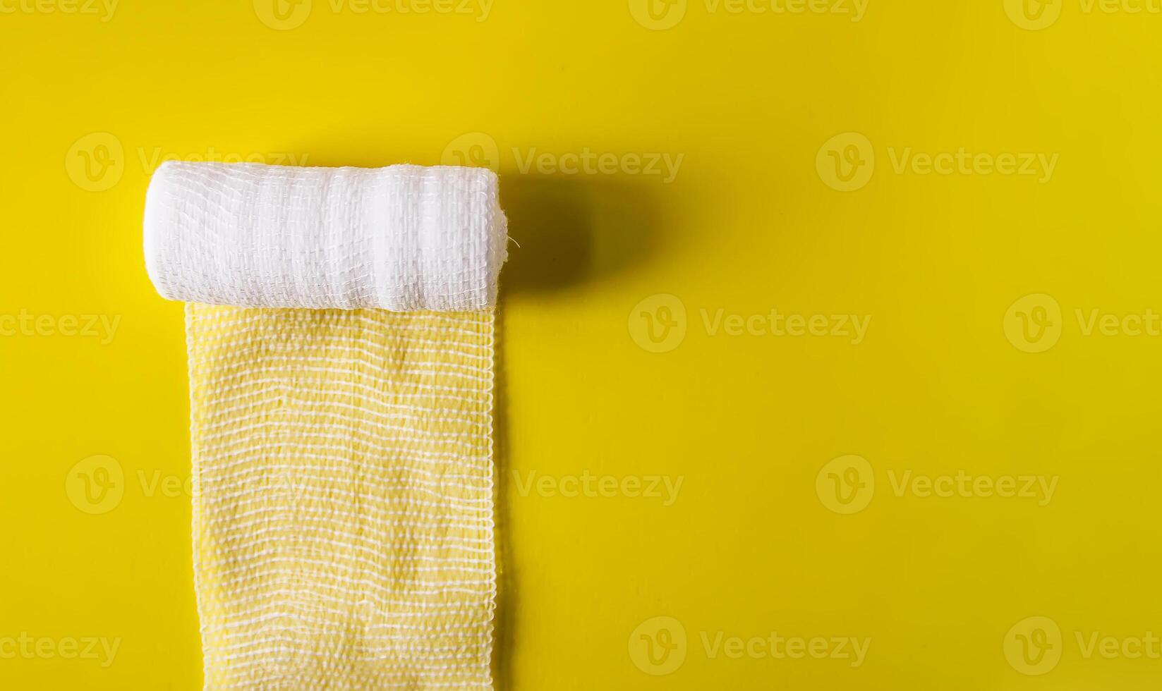 White medical bandage on yellow background close up photo