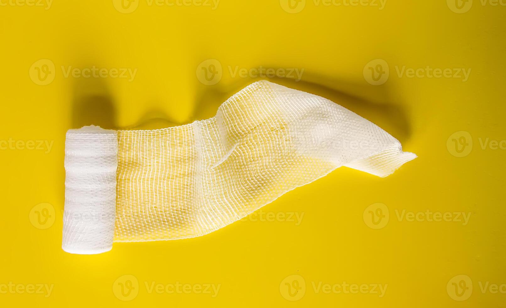 White medical bandage on yellow background close up photo