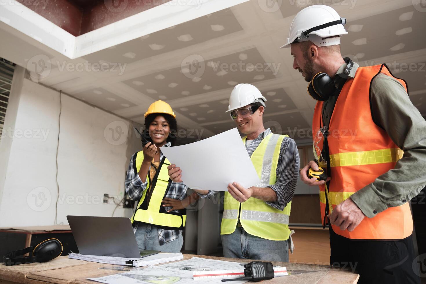 Engineering Team Collaborating on Construction Plans at Worksite with Blueprints and Safety Gear photo